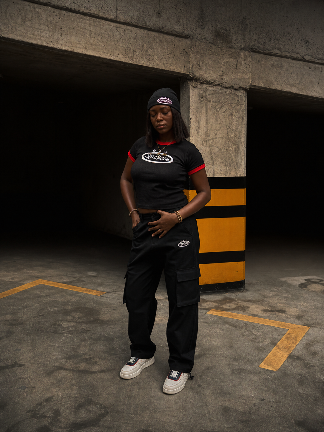 ENSEMBLE model wearing black streetwear in a Lagos concrete parking structure
