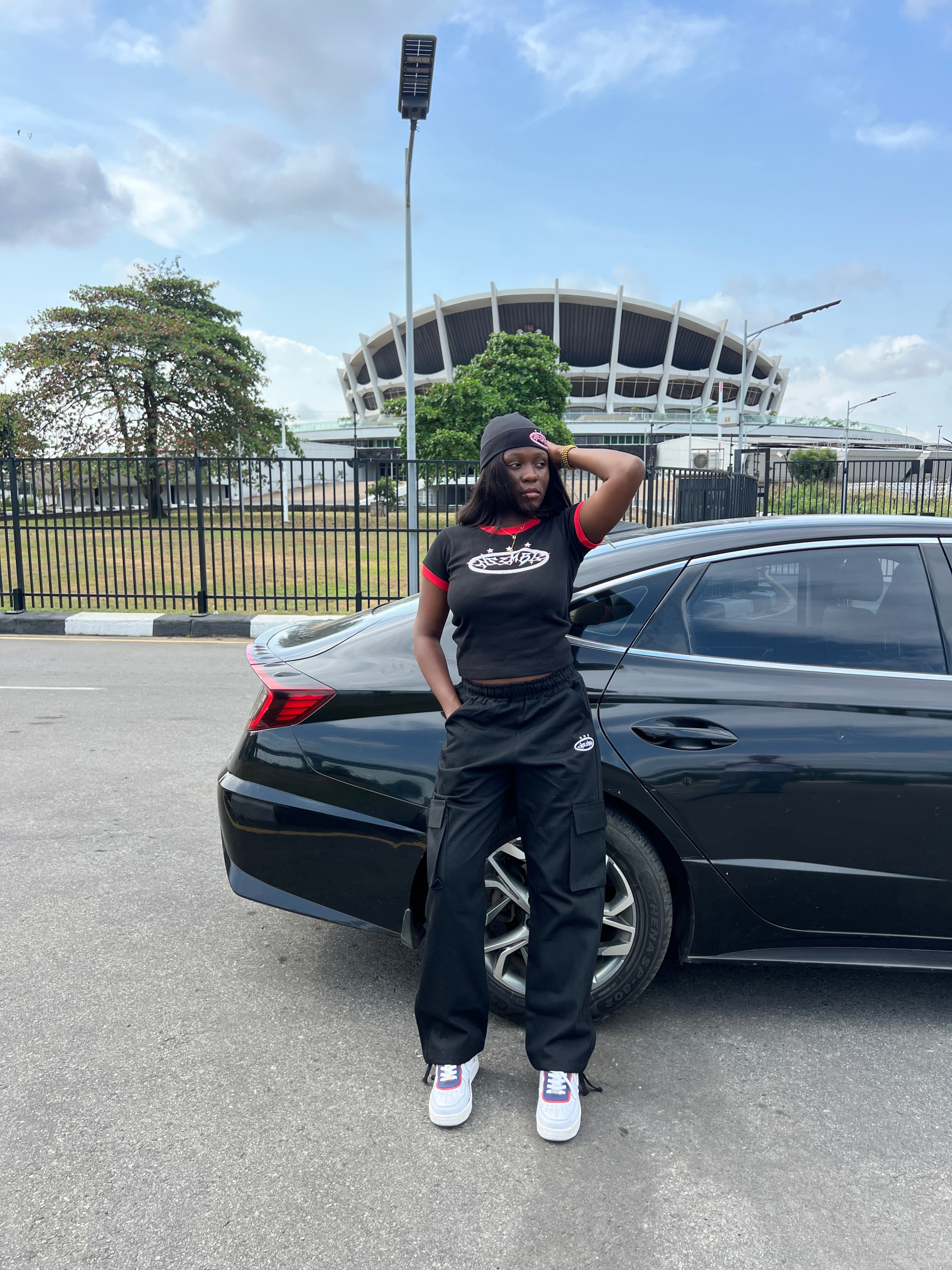 ENSEMBLE model beside a black car near a Lagos stadium